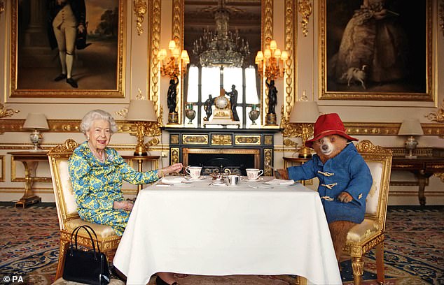 Paddington and the Queen were pictured sitting opposite each other in ornate chairs at a table laid for afternoon tea in an opulent room