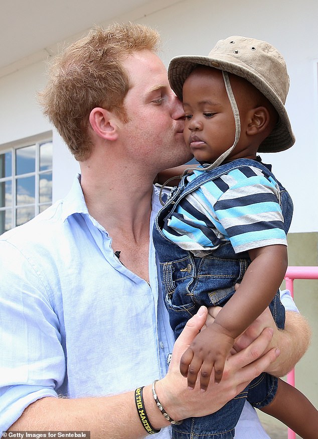 Harry holds a young child during a visit to a children's centre in Bute-Bute, Lesotho, in 2014