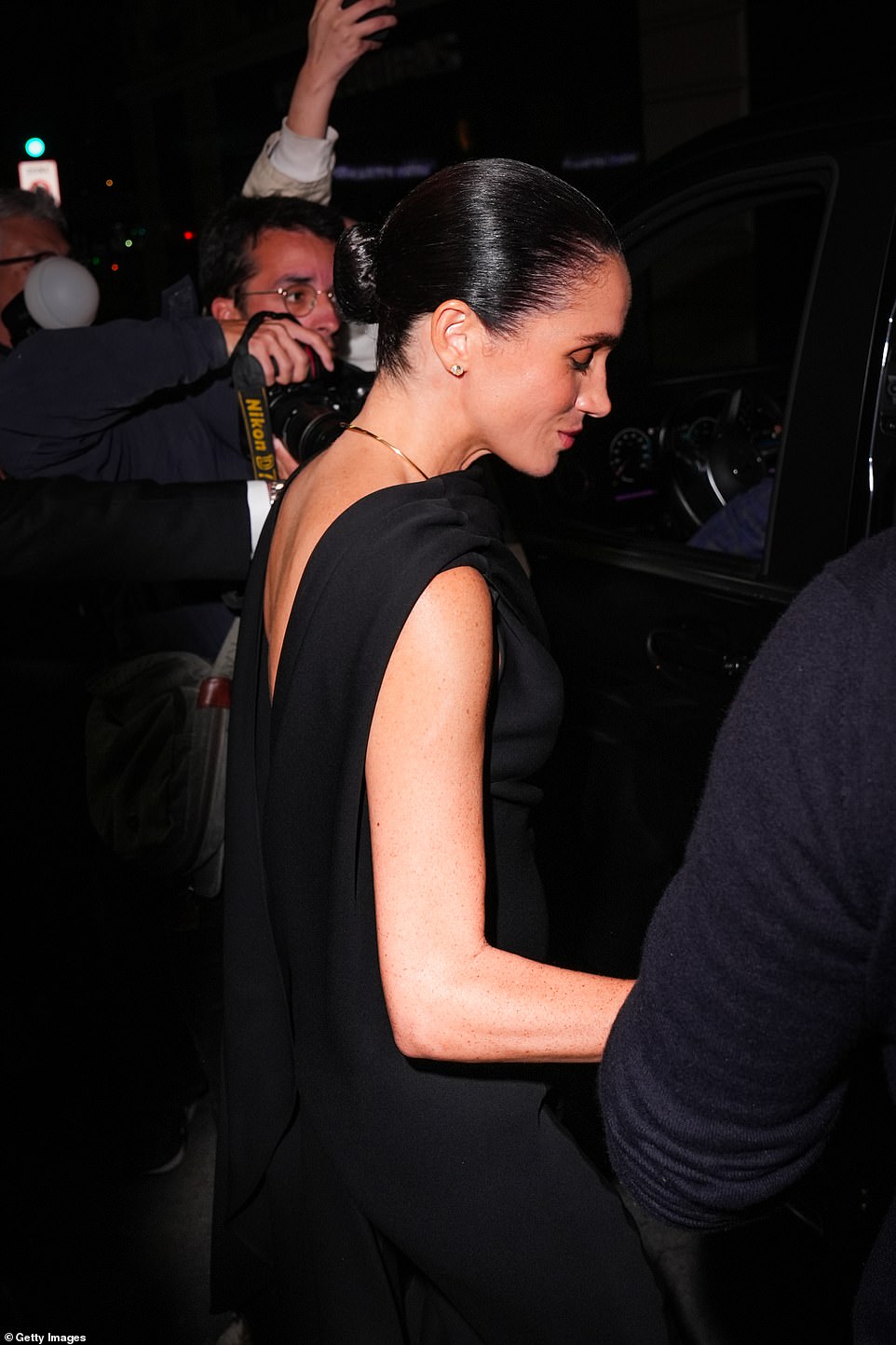 Blooms of white hydrangeas were pictured in the suite where the Duchess was staying. There were glimpses of the team tasked with making the royal look glamorous just hours after the long flight from LA - and also fries, omlettes and other snacks to keep the former royal sustained for her moment in the spotlight. Meghan wore her chocolate brown tresses in an effortlessly elegant slicked back bun and minimal makeup. The Duchess cut an elegant figure in the stylish white oversized button-through ensemble with an incorporated cape and, according to some observers at least, certainly had the strut of a fashionista.