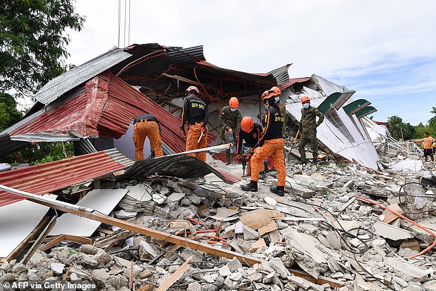 Rescuers search for three people who were reported missing under the rubble of a collapsed building in Bogo City, Philippines, today