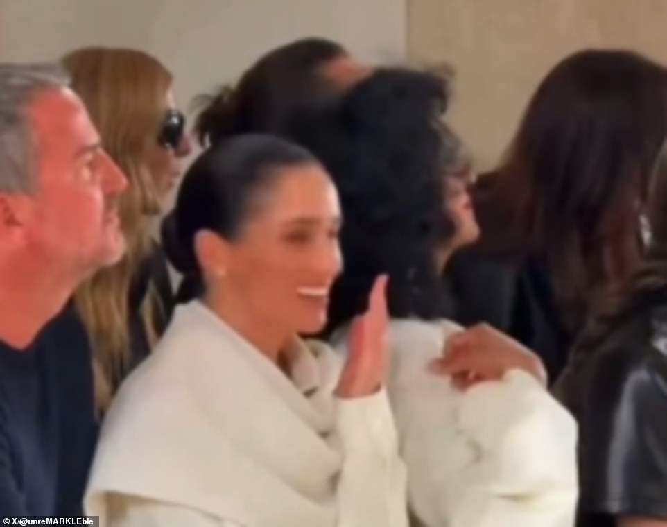 She also shared an awkward kiss with Balenciaga's designer Pier Paolo Piccioli - and ended up butting heads with him as they leaned in for an embrace. In the latest clip, Meghan could be seen watching the fashion show from the front row, sat next to her close friend, Marcus Anderson, Soho House brand's creative director. At one point, the Duchess was seen reacting with amusement, firstly gasping with horror before giggling behind her hands and turning to chat to Marcus, who remained stony-faced. When her friend didn't seem amused, Meghan turned back around to watch the show with a more neutral expression, though a representative insisted she was not laughing at the model falling. One person speculated: 'I think it was someone tripping or falling because the girl behind her mouths 'Oh!' 'Somebody probably fell,' a second said, while a third noted: 'Others react to it, just not as obviously as she did.'