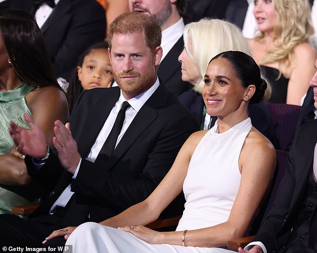 'Sitting in seats in the audience, we can see Meghan sitting to the front of the photo with her hand on Harry’s thigh in a gesture of ownership,' the body language expert told Daily Mail