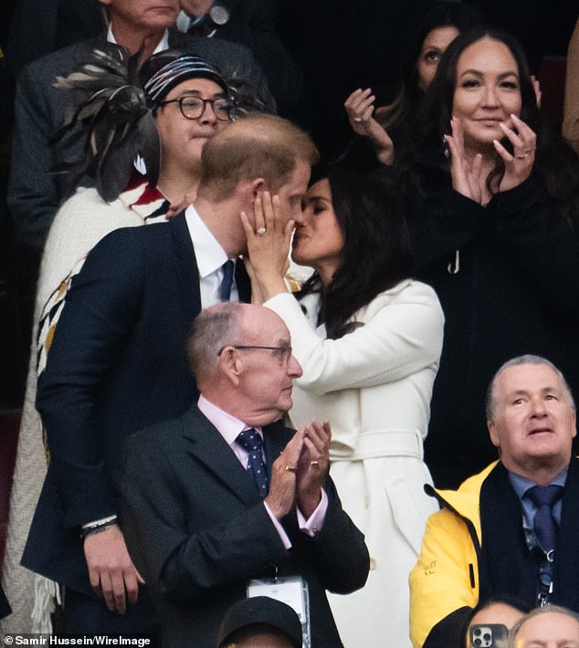 In the above photo from the opening ceremony of the 2025 Invictus Games, Judi points out that Meghan is not only kissing Harry on the lips in the middle of a large audience but she also holds his face to direct the kiss