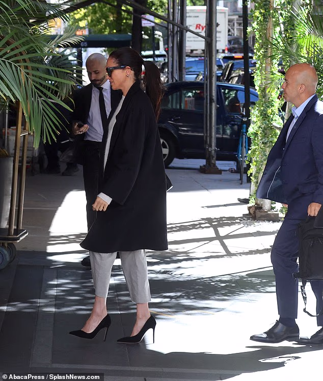 The Duchess of Sussex, 44, sported an elegant black trench coat , stilettos and an all-white ensemble for the autumnal day in the Big Apple, as she was spotted walking into the lobby on Thursday