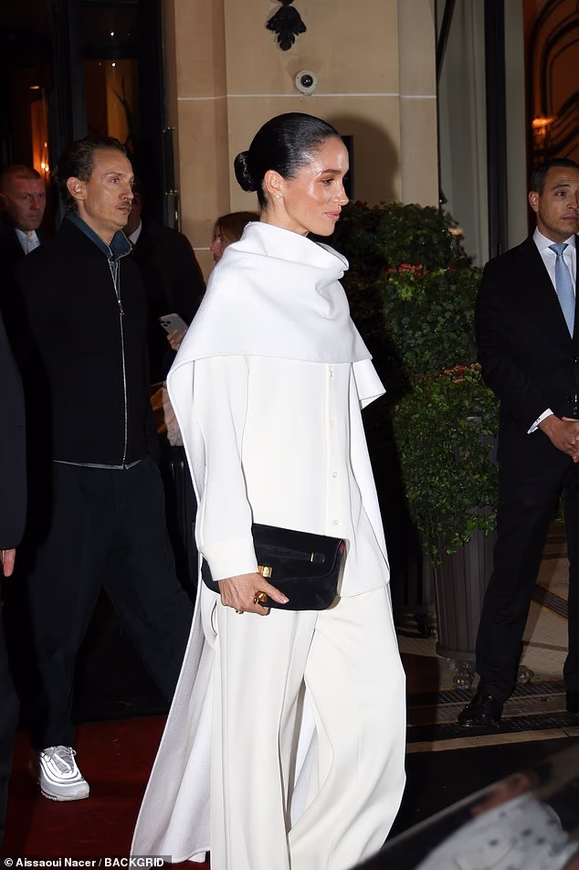 She was snapped wearing a stylish white oversized cape over a white button-down shirt with matching trousers
