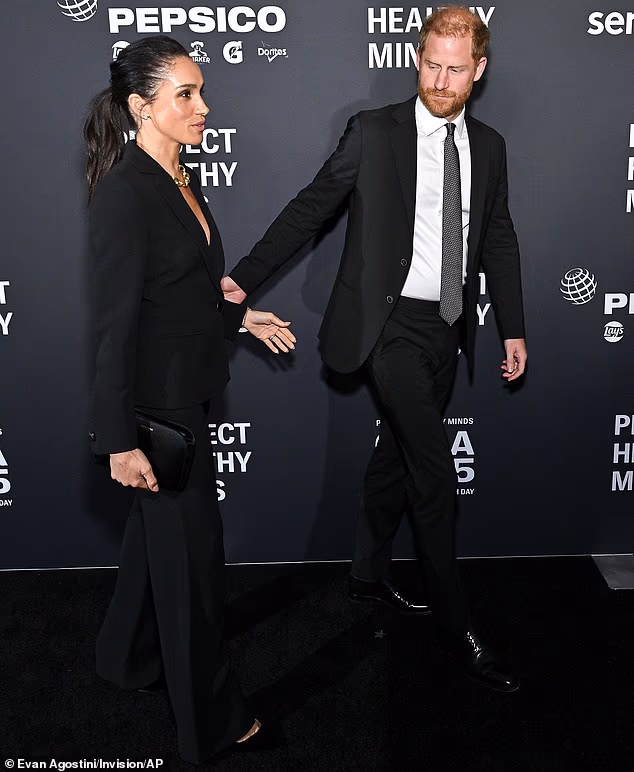 But at one point, the Duke of Sussex appeared to hurry his wife along as they paused for a brief photo session on the red carpet and Meghan was also left alone as Harry held a conversation a distance away