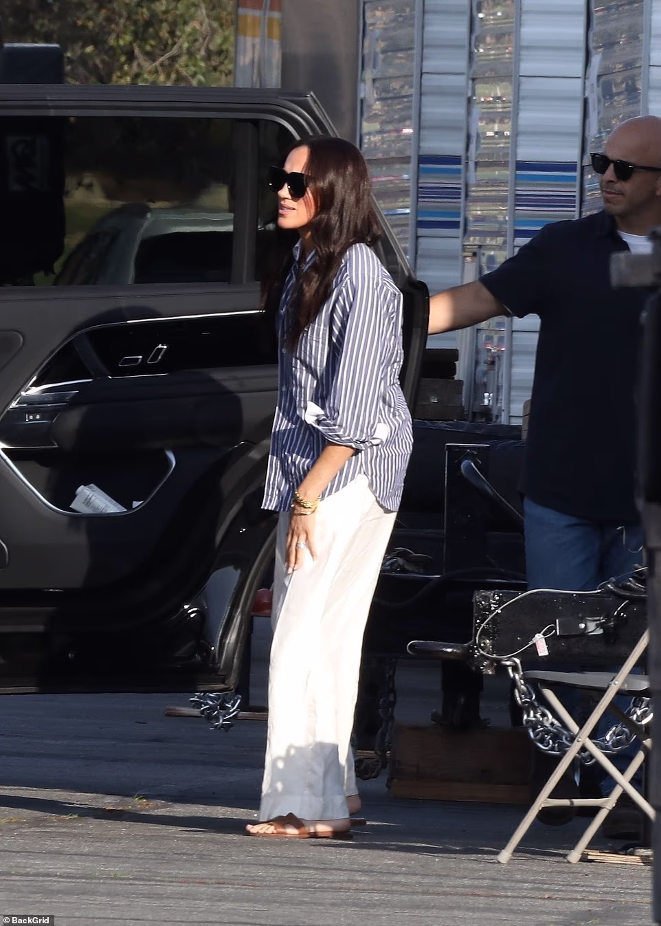 The Duchess, seen wearing a casual white and navy pinstripe shirt, which she paired with an elegant white linen maxi skirt, waved excitedly to a member of the crew. She added brown sandals and chic sunglasses for the warm weather in Pasadena, making for a relaxed look while filming. She also appeared to be wearing her staple £5,850 Cartier love bracelets and Princess Diana 's Cartier watch. Meghan looked delighted as she climbed into a luxurious Range Rover and was swept to a large estate in the hills of Pasadena. There the Duchess, who starred as Rachel Zane in Suits between 2011 and 2018, was filming a scene by the swimming pool for the Amazon MGM Studios production. The mother-of-two is returning to acting eight years after her final scenes in the legal drama when she quit to marry Prince Harry and briefly become a working royal. A source close to the production has insisted that Meghan has been 'swamped with offers' for acting work 'but this one felt right'.