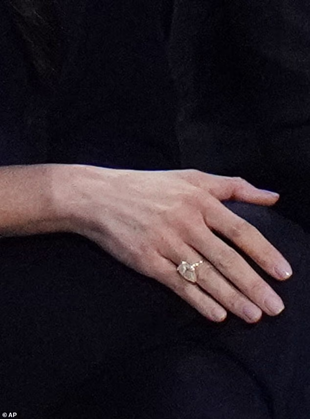 As they waved at the cameras and posed for pictures, a large diamond ring that was not part of her wedding stack caught the light. Pictured: Meghan's new ring