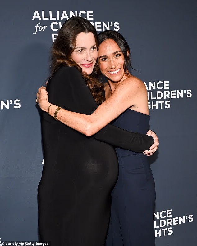The Duchess hugs Kelly as they attended the children's charity bash