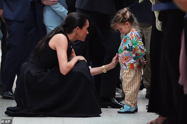 The Duchess, 44, who looked typically stylish in a £920 ($1,250) navy dress from Australian designer Karen Gee, with a young child during the hospital visit
