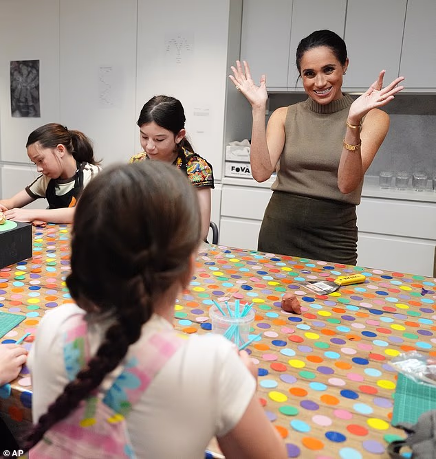 Meghan Markle claps as she takes part in a crafts session