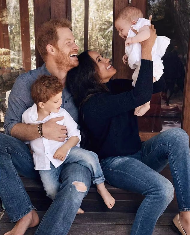 Harry hugs his son Archie as Meghan lifts a baby Lilibet up in the air for their Christmas card picture released in 2021