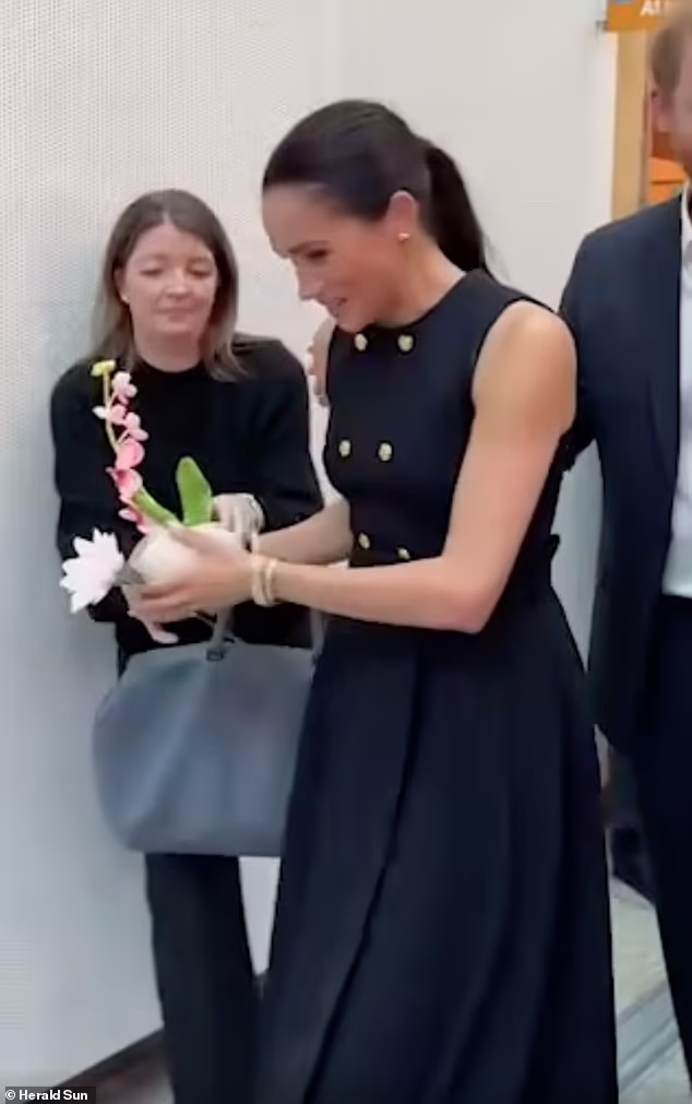 Meghan skillfully hands flowers to an aide in an impressive manoeuvre reminiscent of her days as a working royal