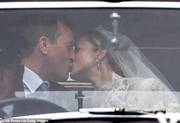 The happy couple were pictured sharing a kiss in the backseat of the sleek claret and black car and smiling at their waving wedding guests