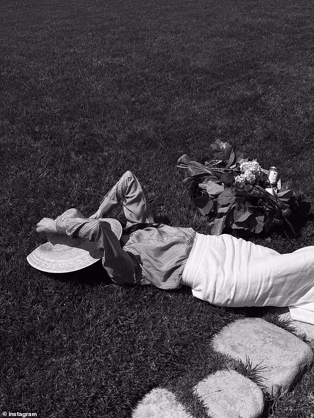 She stuck to the black-and-white theme with another photo of herself in a striped button-up blouse and white linen skirt as she appeared to take a nap in the sun