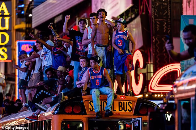 Fans pile onto the top of a school bus in their Knicks jerseys in Times Square