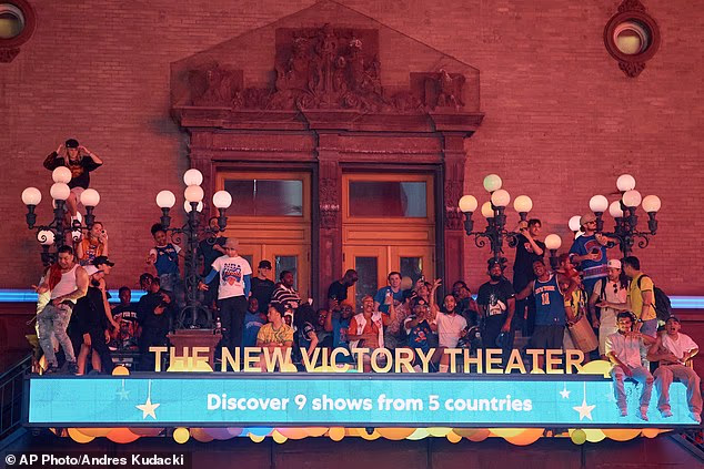 Dozens of fans sit atop the awning of the New Victory Theater on 42nd Street