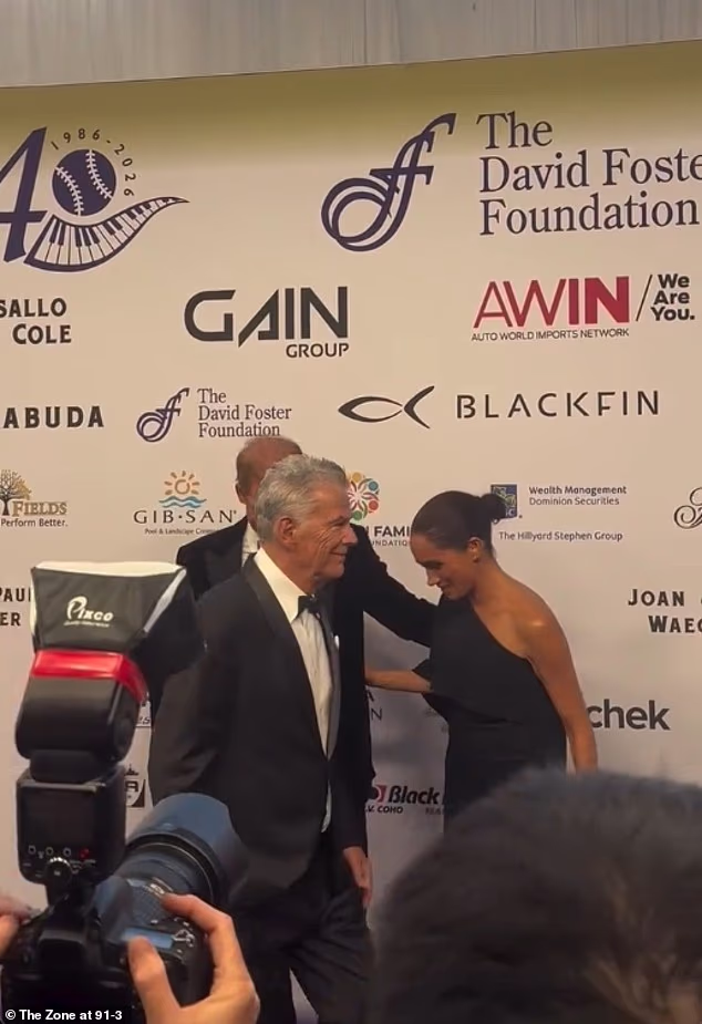 The Duchess of Sussex, 45, played the moment off expertly by quickly tucking her floating arm behind her back before leaning into her tuxedo-clad husband, 41, for a group photo with Foster, 76, and McPhee, 42