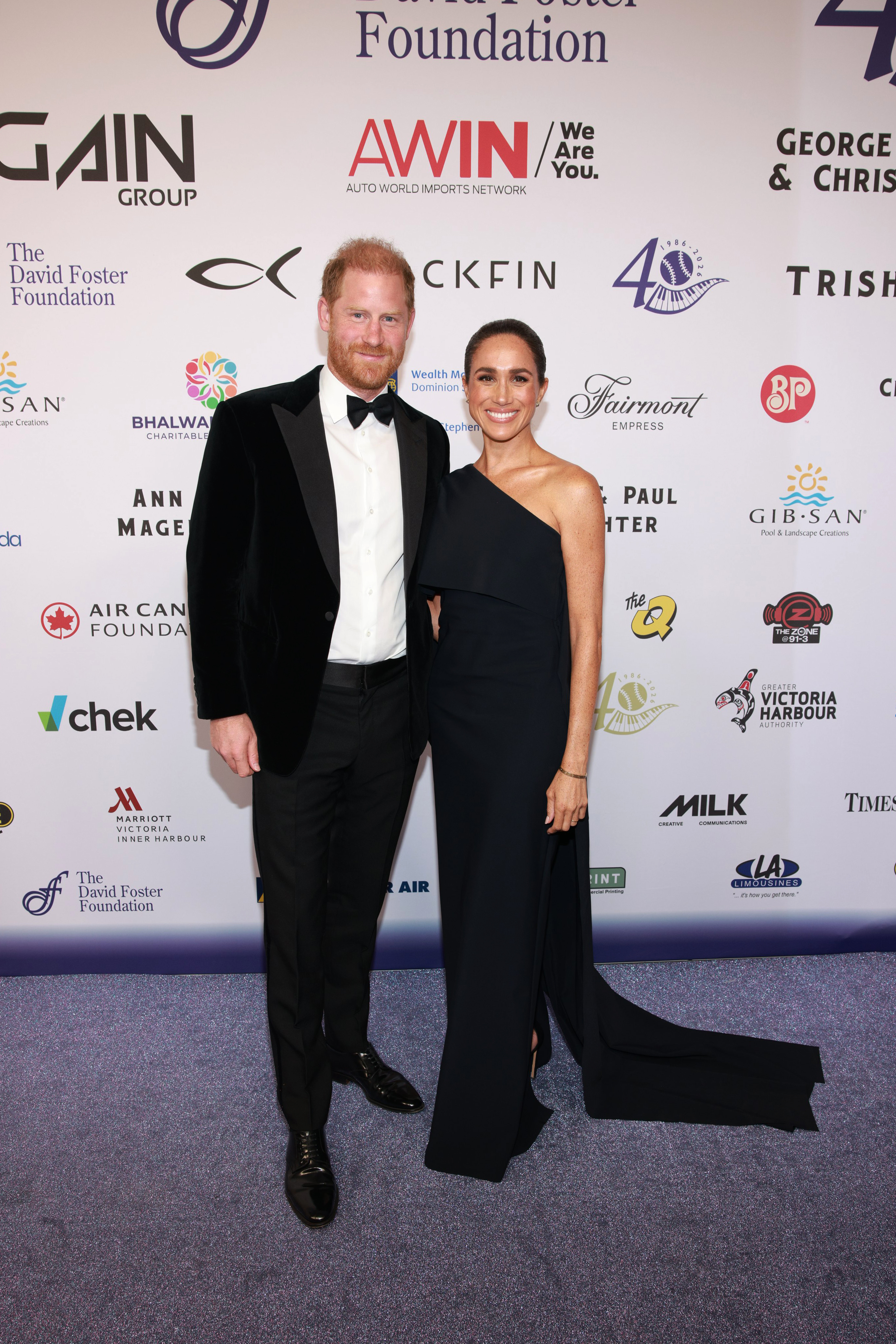 Prince Harry and Meghan Markle in a tux and gown on a red carpet