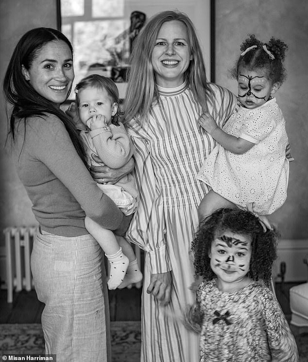 In this picture from Lilibet's first birthday party, the young princess is seen in her mother Meghan's arms beside photographer Misan Harriman's family which includes his wife Camilla Holmstroem