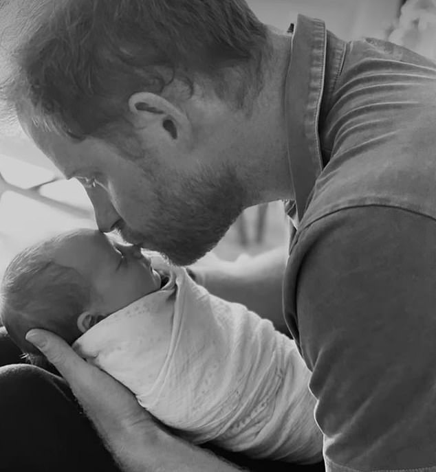 A stunning black and white portrait shows Harry gently kissing Lilibet on the nose, with the sweet little girl swaddled as he cradles her in his hands