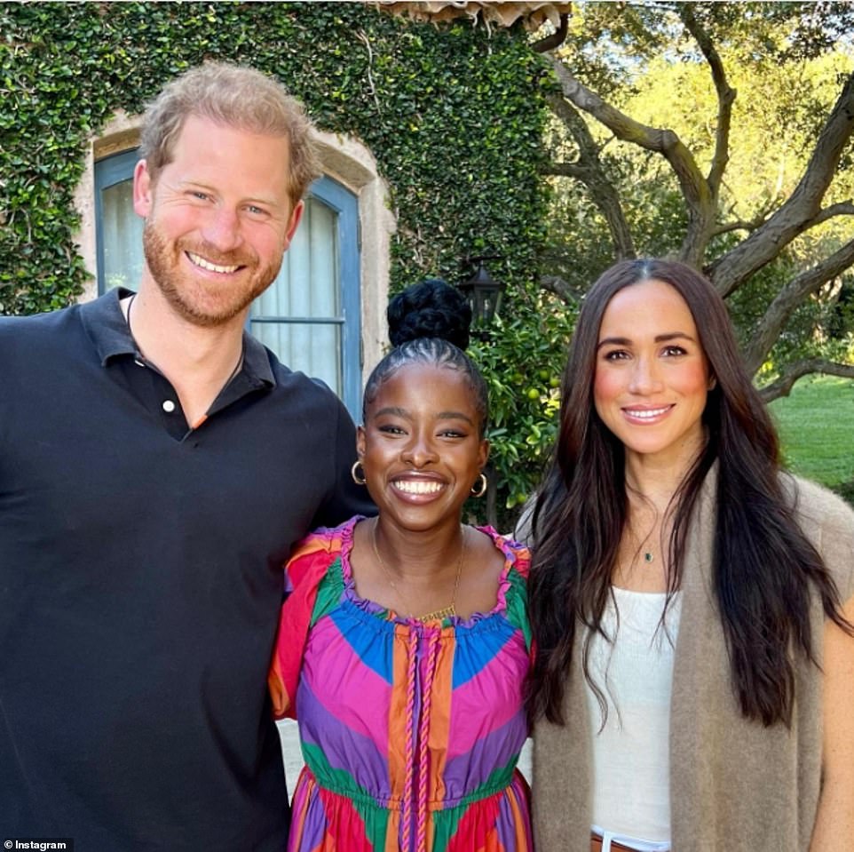 Looking typically stylish, mother-of-two Meghan, who has son Archie, three, and 17-month-old daughter Lilibet with husband Harry, opted for a brown cardigan, teamed with a white top. She cinched her waist with an elegant brown belt, while adding a touch of glitz to her ensemble with a dainty emerald necklace. Her hair was left straight and down for the meeting with Amanda, while she sported a smattering of glamorous makeup. Prince Harry beamed for the camera, dressed in a simple blue shirt, which was set outside in front of a building covered with greenery. Amanda, meanwhile, commanded attention in a colorful outfit, paired with a golden necklace and hoop earrings.