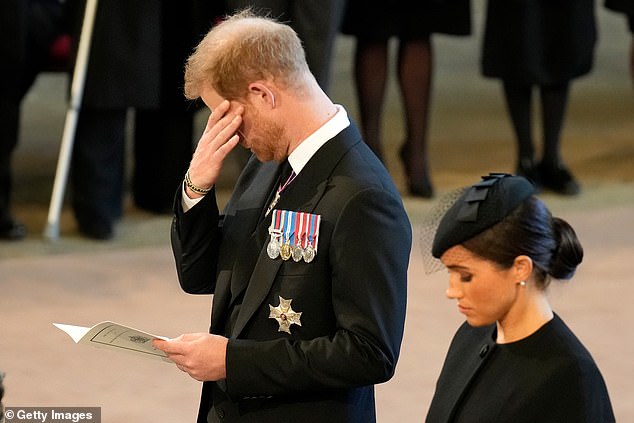 Photos captured a poignant moment for the Duke of Sussex (left with the Duchess of Sussex right) as he held his head in his hand, shielding his eyes, and looked down as the Queen's coffin was moved inside the Palace of Westminster