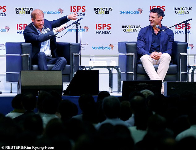 A staff member applauds as Prince Harry walks on stage at the summit in Tokyo today