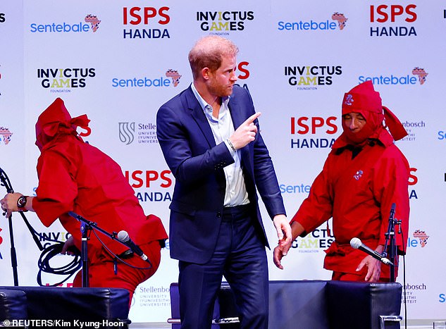 Workers in ninja attire arrange the stage while Harry talks to other participants in Tokyo today