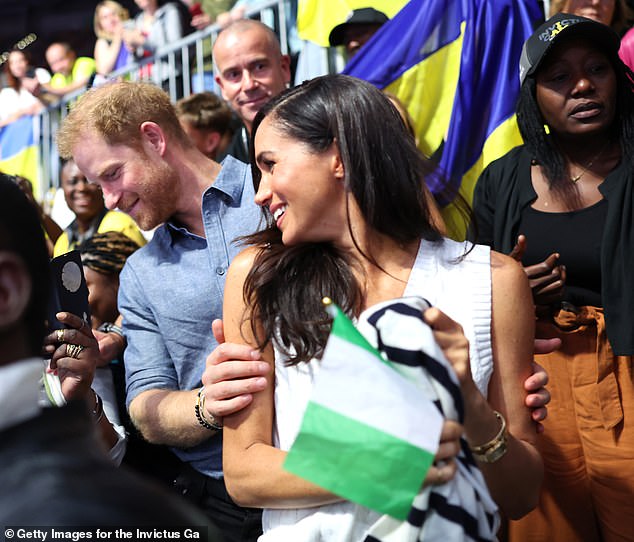 Harry places his hand on Meghan's arm on Thursday as the pair interact with fans at the Ukraine v Nigeria volleyball match