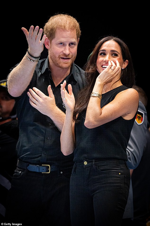 Harry points something out to his laughing wife during the wheelchair basketball final between the US and France