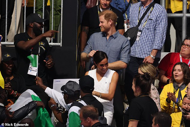 Harry is seen dancing in the crowd as Meghan interacts with adoring fans