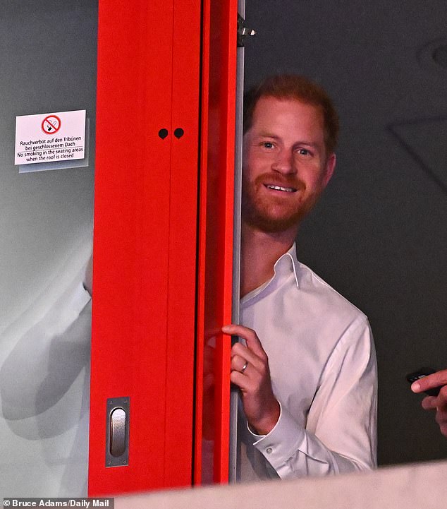 Harry peers out of a window as he starts to watch the seated volleyball