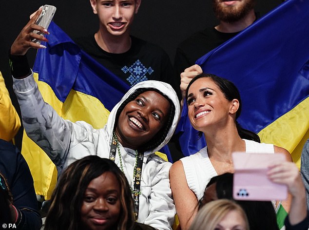 Selfie queen! The Duchess of Sussex strikes a pose with a person sitting next to hear while watching the volleyball competition at the Invictus Games