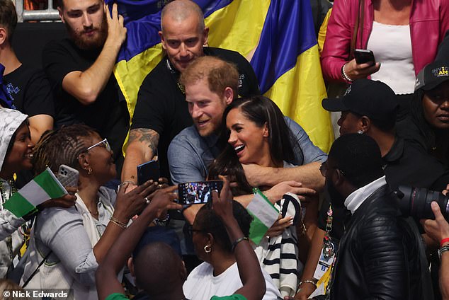 In one shot, the Duke of Sussex, 38, embraced his wife, 42, as she grinned and leaned back into him