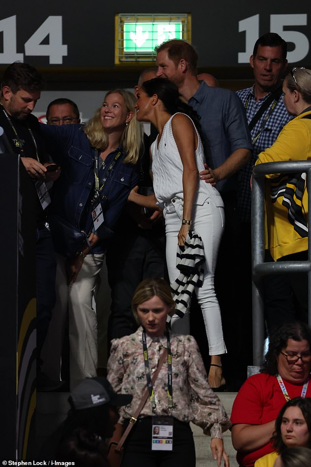 Elsewhere, a protective Harry placed his hand on Meghan's waist as he led her past excited well-wishers