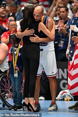 Meghan (pictured hugging contestants) showed her allegiance to the US team by sporting a stars and stripe flag on her jumper