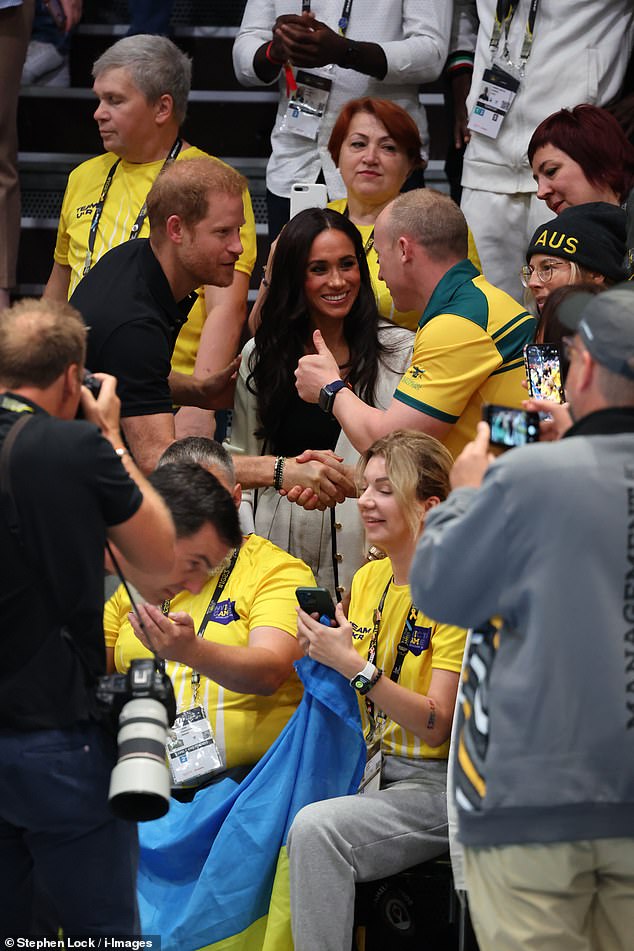 Prince Harry and Meghan Markle greet a member of the crowd in Dusseldorf this morning