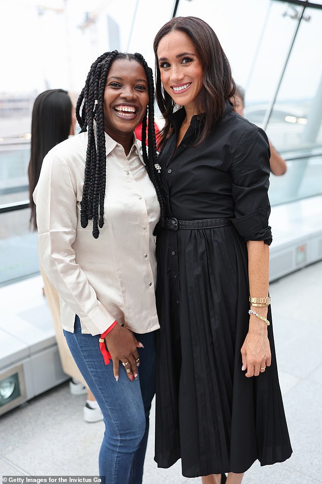 Meghan pictured smiling as poses for a photo with athlete Glory Essien