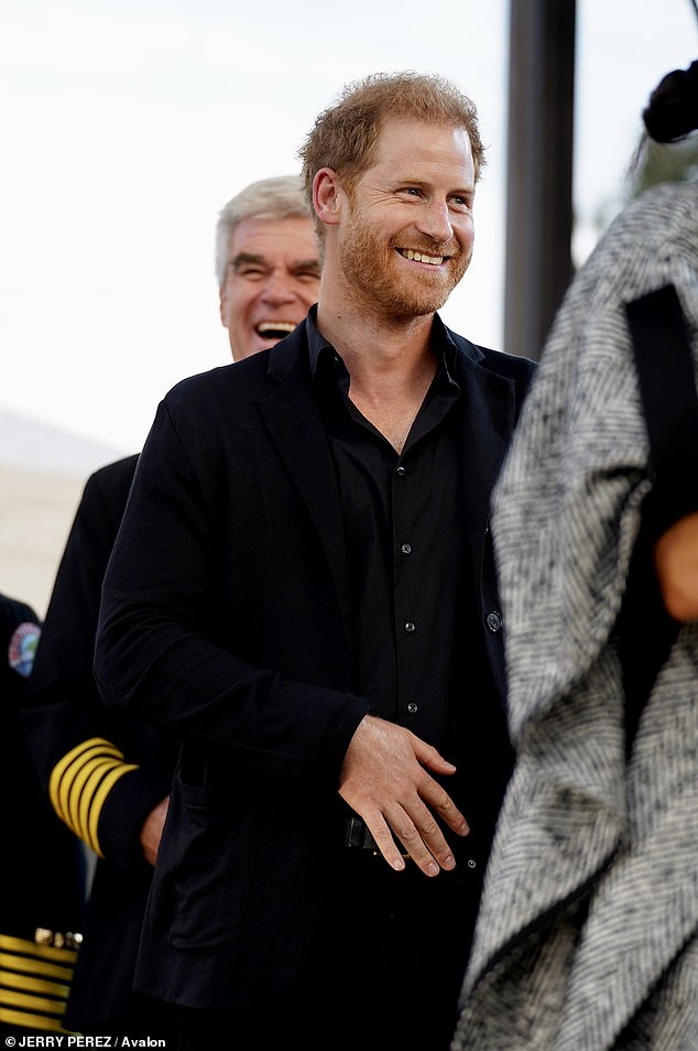 Harry smiles as he and the Duchess are introduced as special guests at the charity event