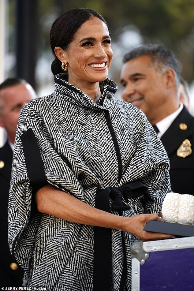 Meghan beams as she attends the charity event dressed in a monochrome coat