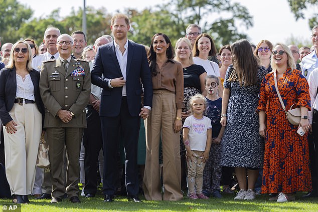 She added her £5,000 Cartier love bracelet to the look as she walked hand-in-hand with Prince Harry