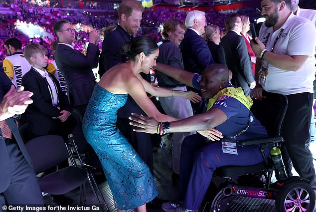 The Duchess of Sussex goes in for a welcoming hug an adoring fan at the closing ceremony last night