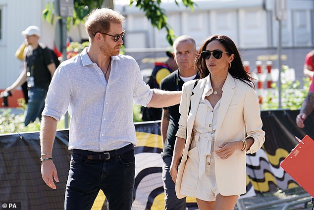 Harry puts a hand on his wife's shoulder as they arrive at the Merkur Spiel-Arena this morning