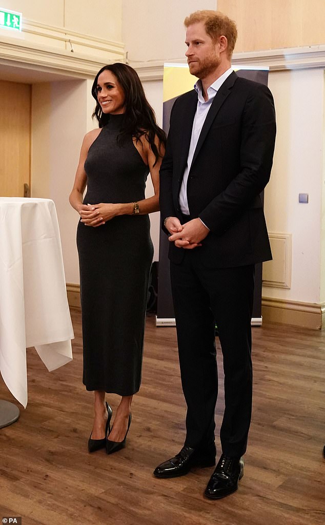 Meghan beamed as she stood next to her husband Harry, who had a more subdued facial expression, as they attended the event