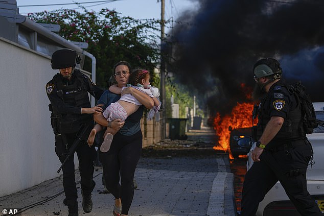 ASHKELON, ISRAEL: Police officers evacuate a woman and a child from a site hit by a rocket fired from the Gaza Strip