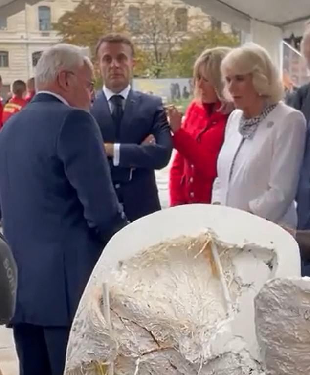 In a clip filmed outside the Notre-Dame in Paris, Brigitte Macron was pictured picking a piece of lint off her husband Emmanuel's suit