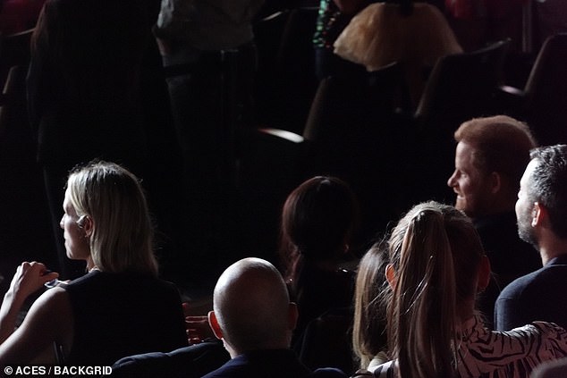 Prince Harry can be seen smiling as Meghan looks in his direction