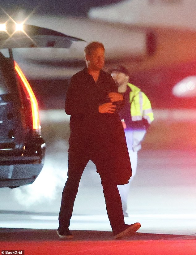 Prince Harry holds his jacket after exiting a blacked-out car following the Katy Perry concert in Las Vegas