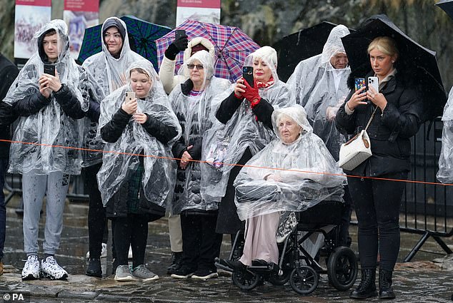 Stoic support: A group of royal fans, wearing plastic rain macs, patiently await the arrival of the king and queen